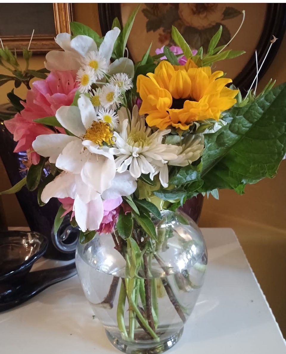 Sunflower and garden-picked bouquet in glass vase
